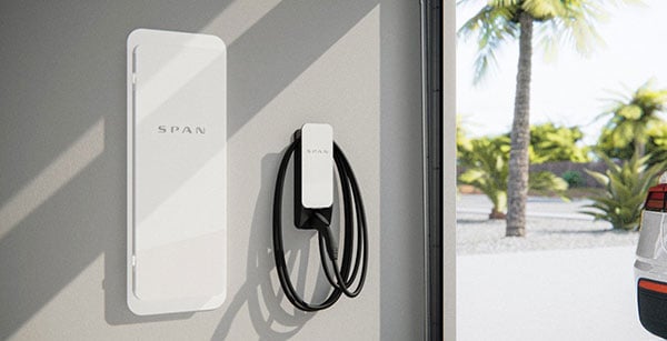 A SPAN electric vehicle charger mounted on a wall with a cable neatly coiled next to a window overlooking palm trees and a parked car.